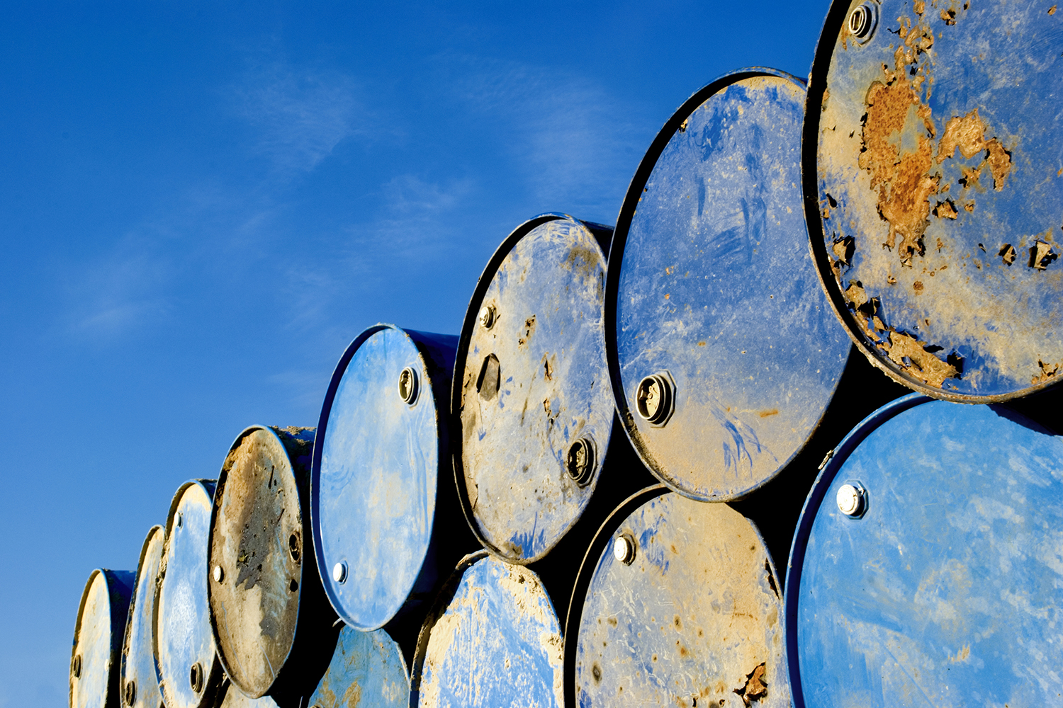 Batch of old rusty barrels against the blue sky