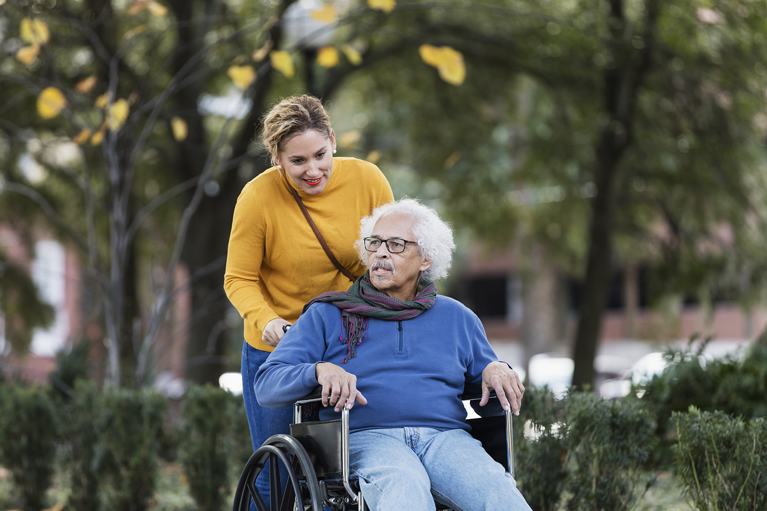 A young woman is helping a person using a wheelchair.