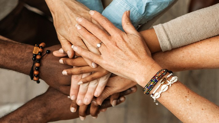 Closed up of a group of diverse people holding hands.