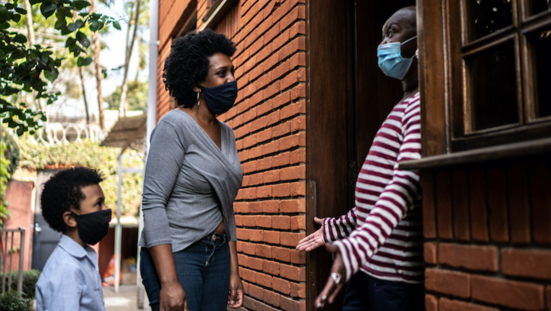 Neighbors talking outside with masks on.