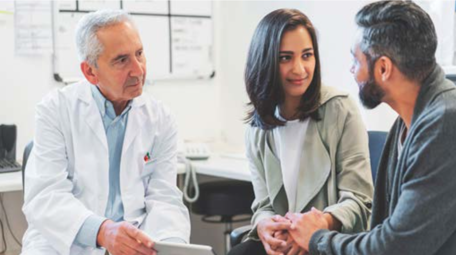 A doctor speaking to a couple holding hands