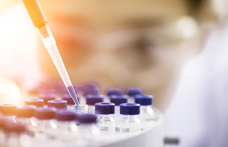 Química femenina pipeteando líquido en viales de muestra Química femenina pipeteando líquido en viales de muestra