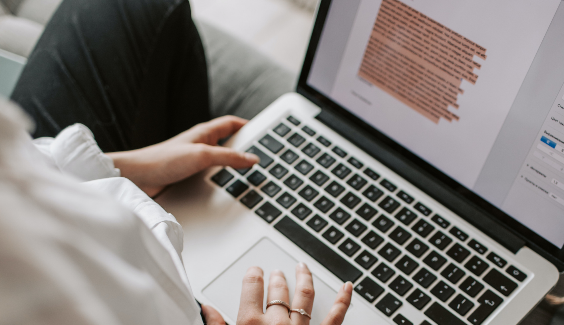 A person in a white top and black pants is holding a laptop.