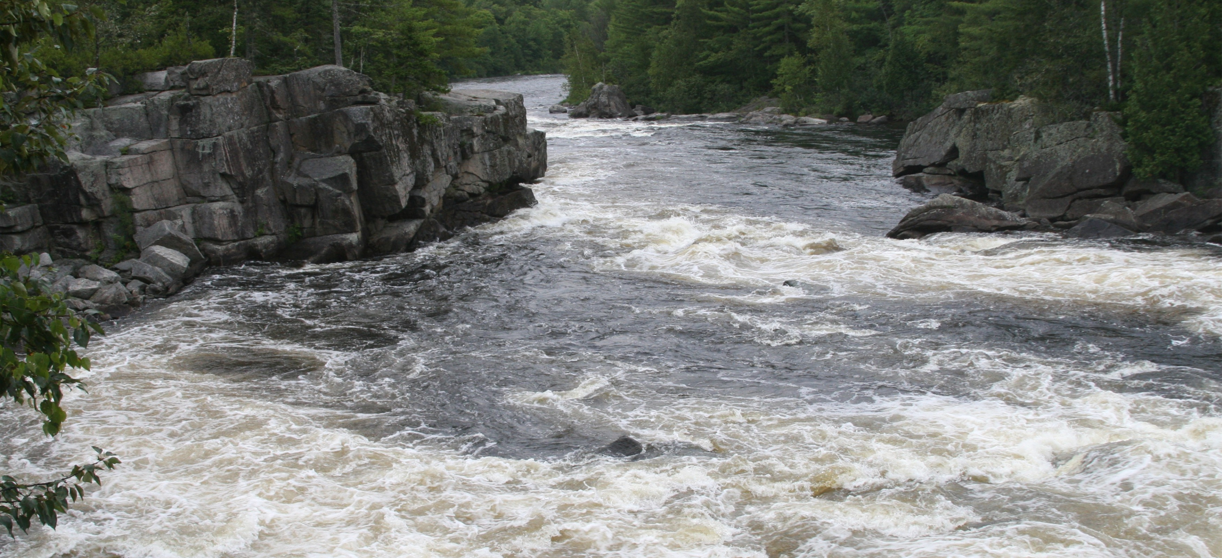 A flowing river through a valley of forest and rocks.