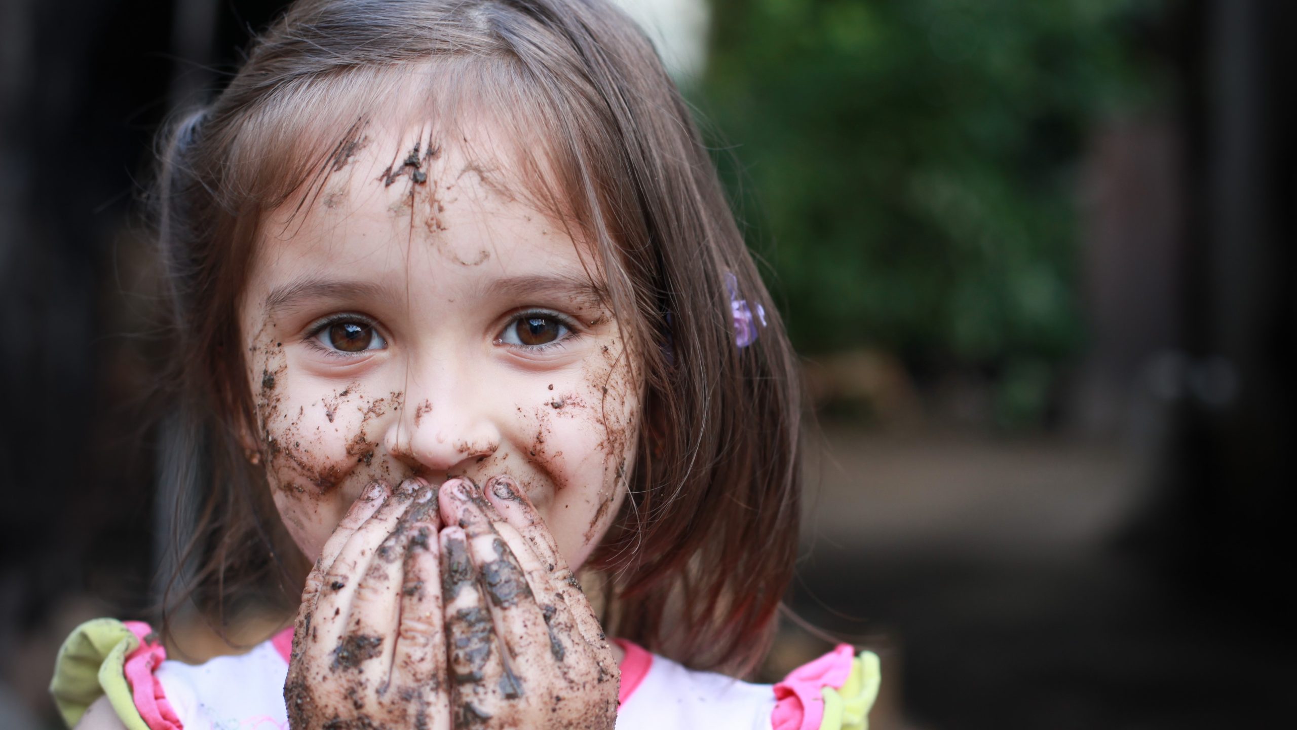 Happy girl with mud on her hands and face