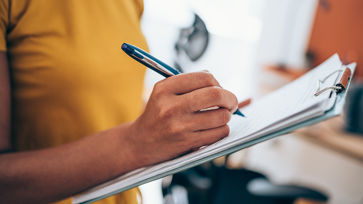 Woman writing on clipboard with a pen.