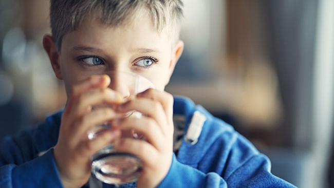 Little boy drinking a glass of water