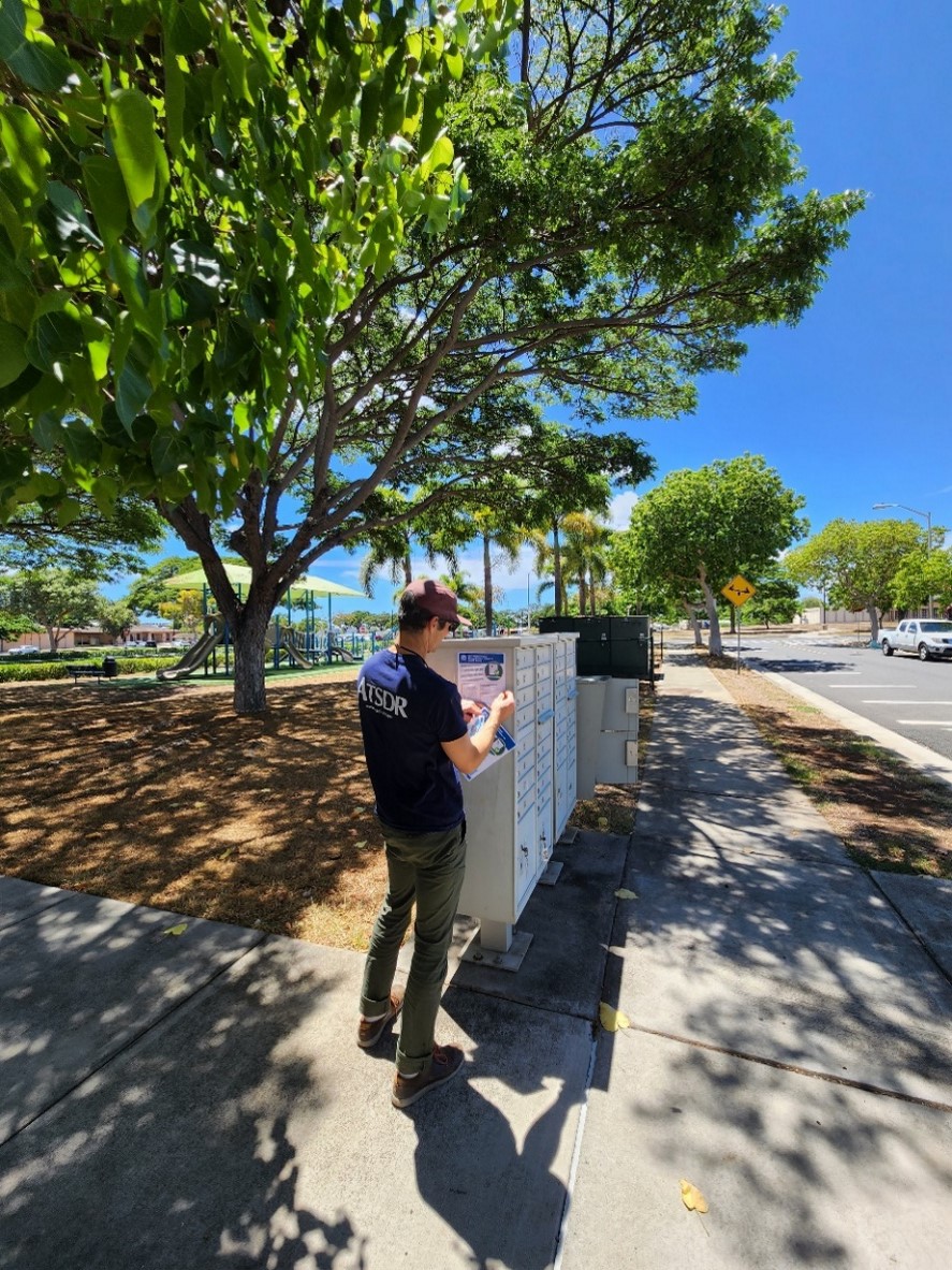 ACE investigation team member tapes flyers to a block of community mailboxes.