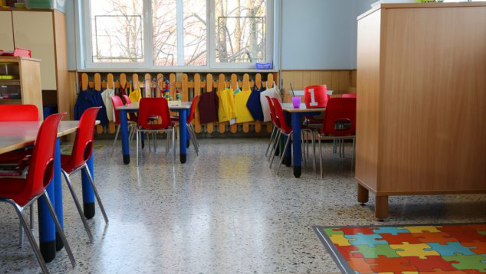 An empty classroom featuring small desks and chairs.